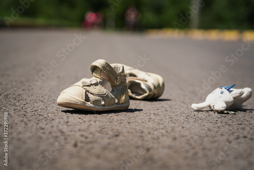Obraz na płótnie children's shoes on the road after dangerous traffic incident w salonie