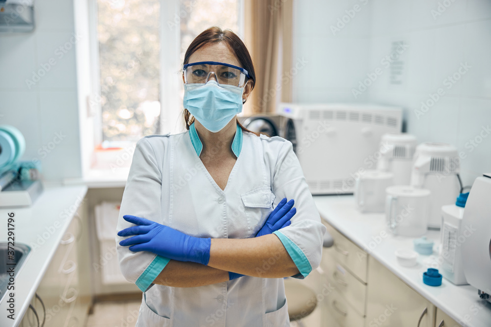 Woman wearing white uniform and blue gloves standing in the workplace Woman wearing white uniform and blue gloves standing in the workplace