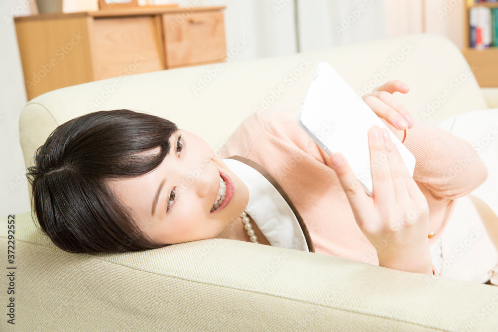 Obraz premium ソファでスマホを見る女性