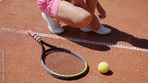 Teenage girl tying shoelaces on the court. © Довидович Михаил