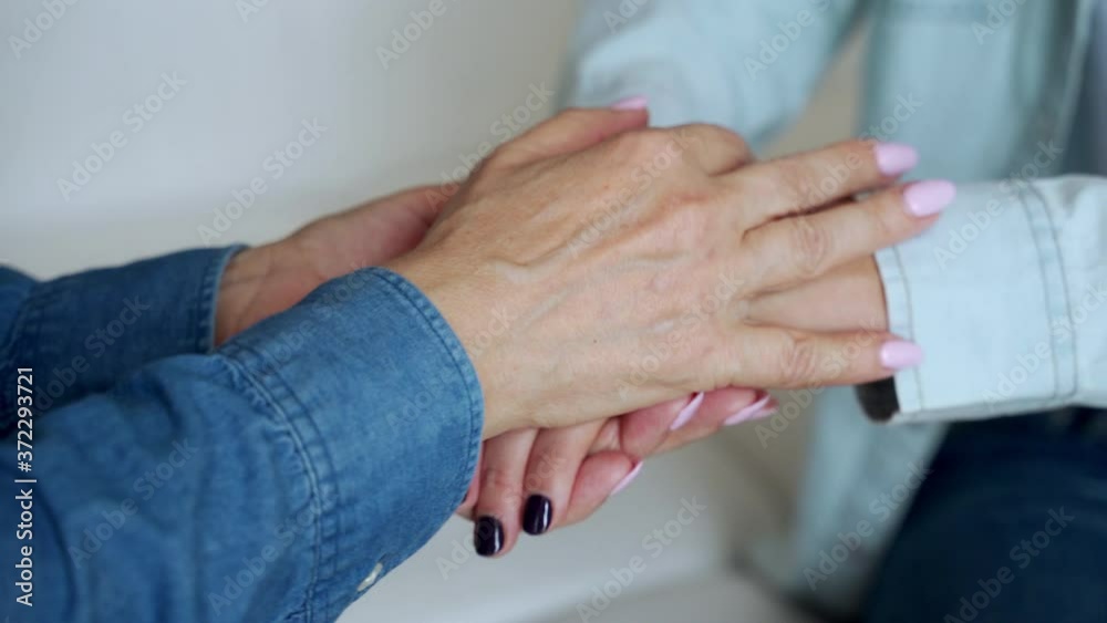 The hands of an elderly woman touch the hands of a young woman The hands of an elderly woman touch the hands of a young woman