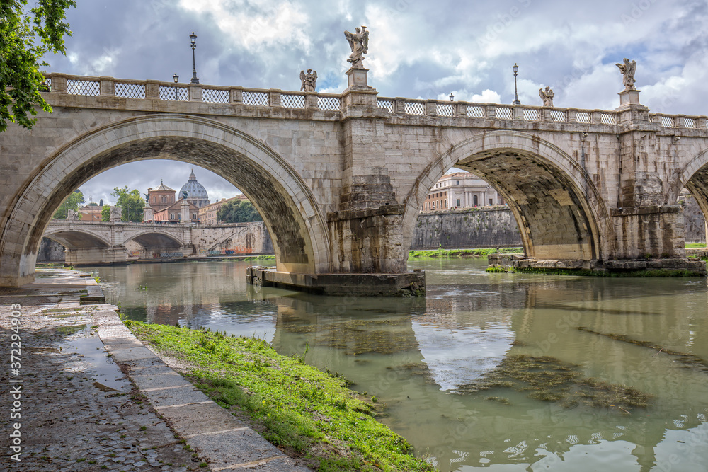 Ponte Sant’Angelo: Rome’s Bridge of Angels. Scenic view of the the Tiber river, the Sant`Angelo bridge and St Peter's Basilica - landmarks of Rome, Italy