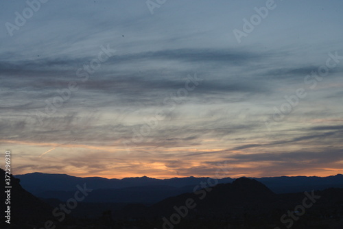 Its right after sunset in southern California desert  with a colorfully illuminated sky  while a mountain range is silhouetted landscape.  The daram created with light and cloud formation . 