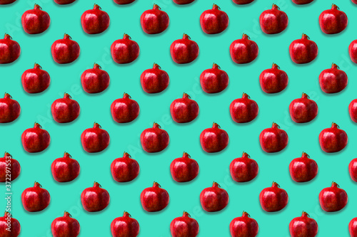 Seamless pattern of red pomegranate fruit on neo mint background. © larisa_stock