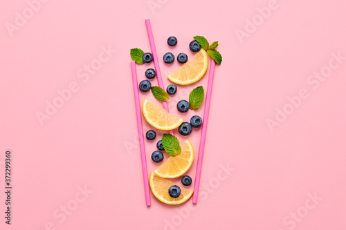 Blueberry, lemon, mint summer beverage on pink background. Bilberry cocktail closeup, top view. Fresh lemonade citrus slices, blueberry. Creative fun concept, fashionable trendy, flat lay