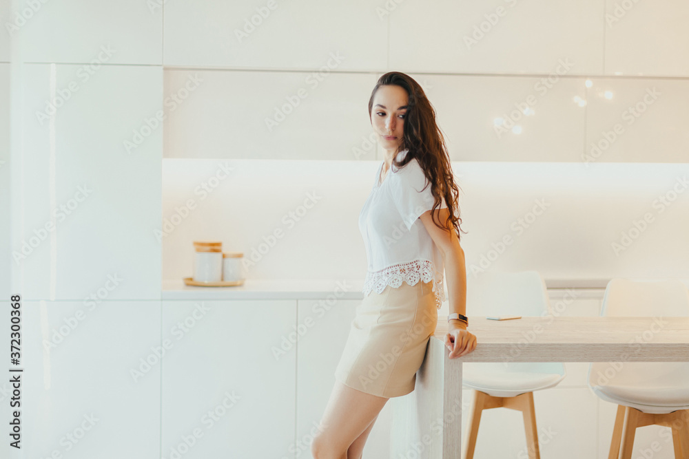 Sad young woman is standing in light kitchen with minimalistic design Sad young woman is standing in light kitchen with minimalistic design