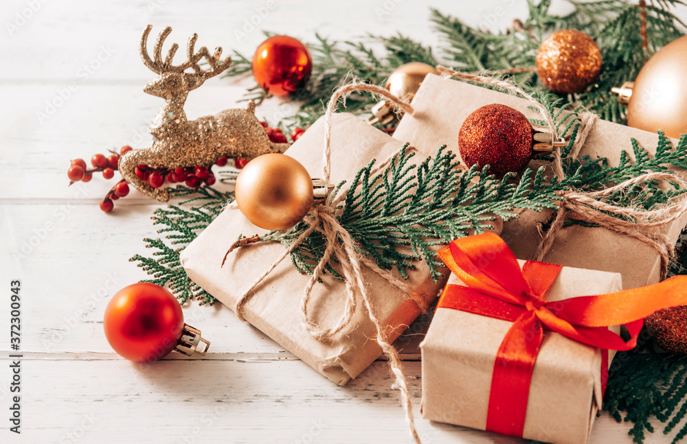  gifts on spruce branches, Golden and red Christmas balls, cones, toy deer, white and red bows on a white wooden background, Christmas still life,