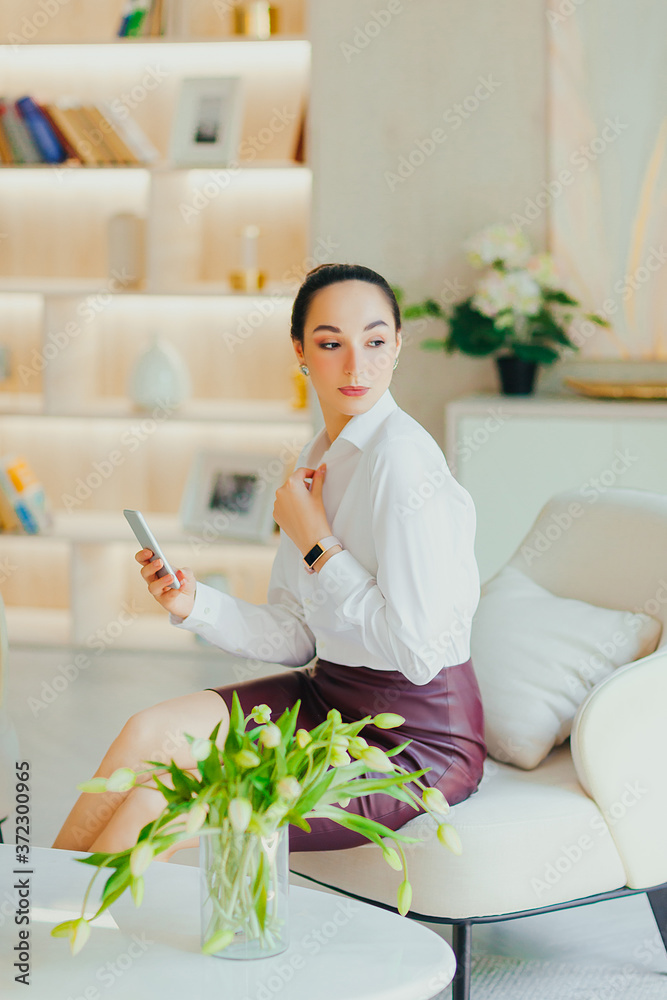 Young beautiful woman is sitting in chair and using phone