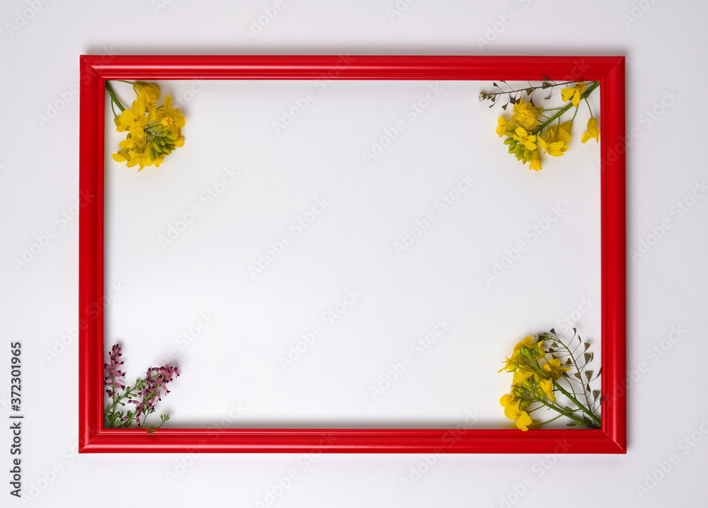 Obraz premium Red wooden picture frame decorated with small yellow flowers on white background.