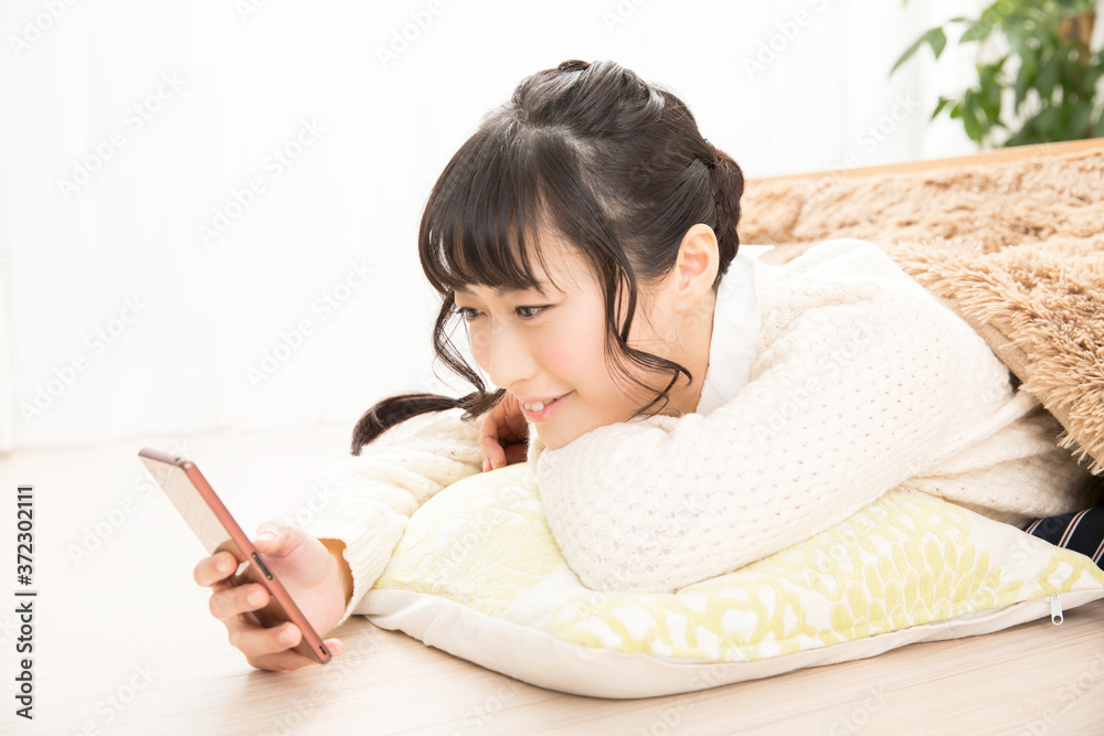 こたつで携帯電話を見る女性 こたつで携帯電話を見る女性