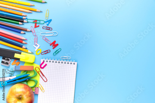 Many different school supplies on blue copy space background. Back to school concept.