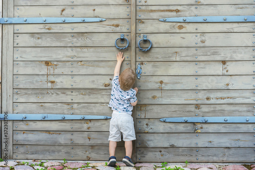 Child trying to open huge outside doors. Reach unreachable. photo