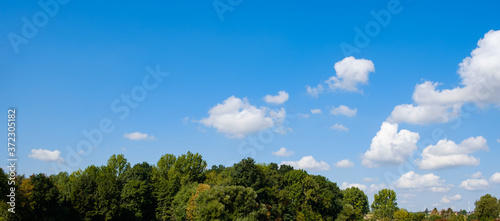 Photography Panorama of a blue sky with some fluffy white cumulus clouds at the right with t