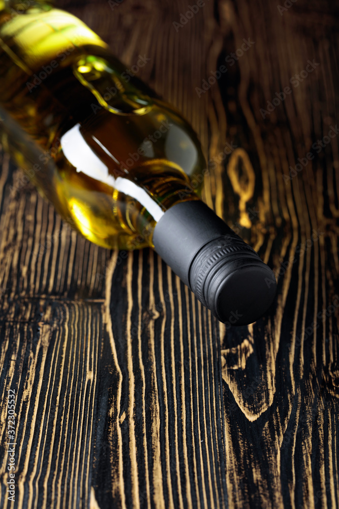 An unopened bottle of white wine on an old wooden background.