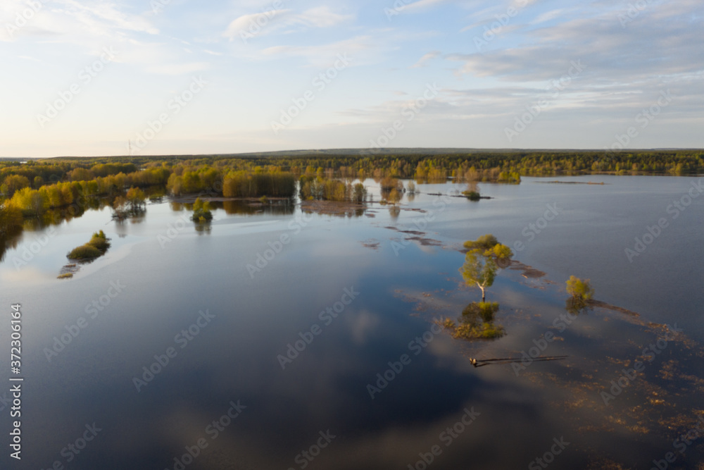 Spring flooding on the river, flooded forest, islands on the river. View from a drone, a bird's-eye view. View without the presence of people in the evening. 