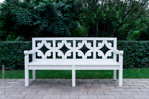 Fototapeta Naklejka Na Ścianę i Meble -  White vintage style bench in the park on green foliage background.