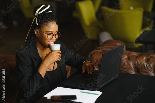 Satisfied african girl using laptop at cafe, working online, copy space