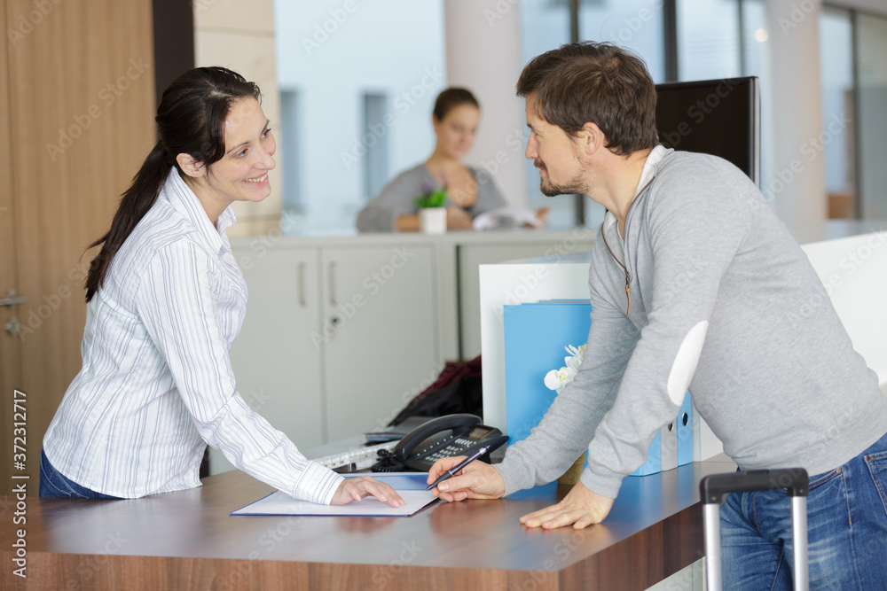 man signing in at reception desk man signing in at reception desk