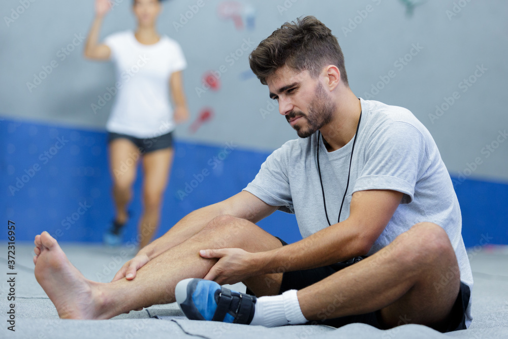 man suffering from pain in leg while sitting on floor man suffering from pain in leg while sitting on floor