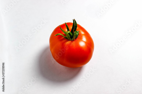 A ripe red tomato on a white background with a clear shadow.