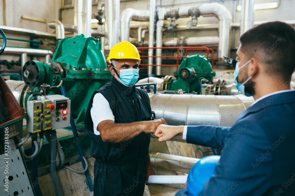 businessman and worker handshake indoor industry plant, covid protected with face masks businessman and worker handshake indoor industry plant, covid protected with face masks