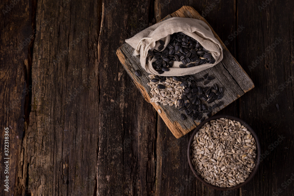 sunflower seeds in a linen bag, peeled without peels in a bowl on a dark wooden background. copy space