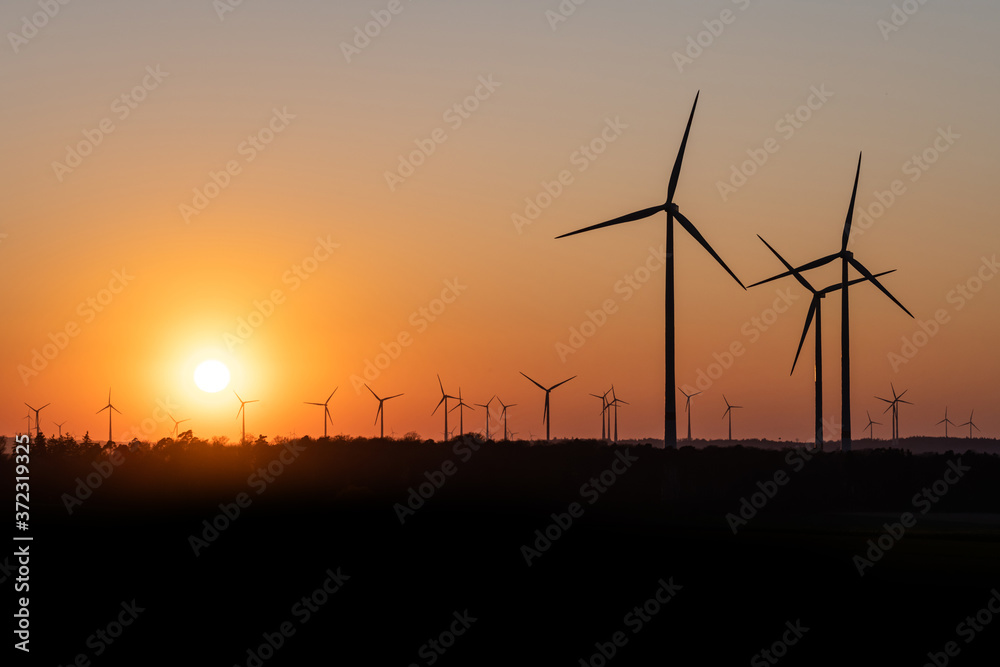 Black Silhouette of windturbines energy generator on amazing sunset at a wind farm in germany