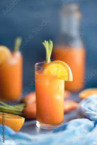 Fresh orange and carrot juice on blue background.