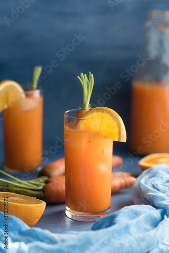 Fresh orange and carrot juice on blue background.