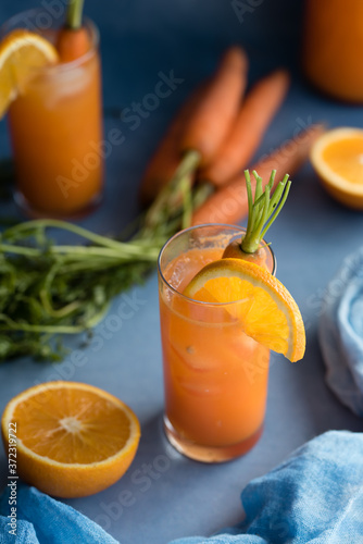 Fresh orange and carrot juice on blue background.