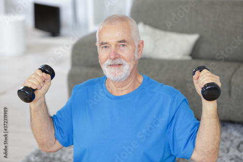 senior man listing weights at home