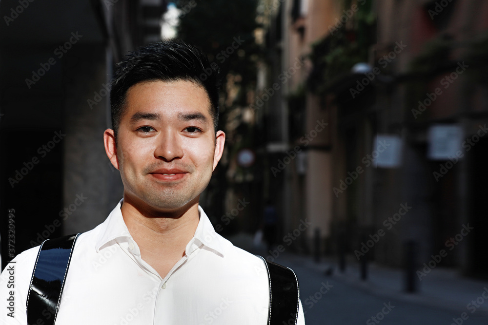 Fototapeta premium Portrait of happy young Chineese man posing on the street with smile on his face. Lifestyle concept.
