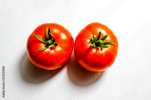 Two red tomatoes on a white background with clear shadows.