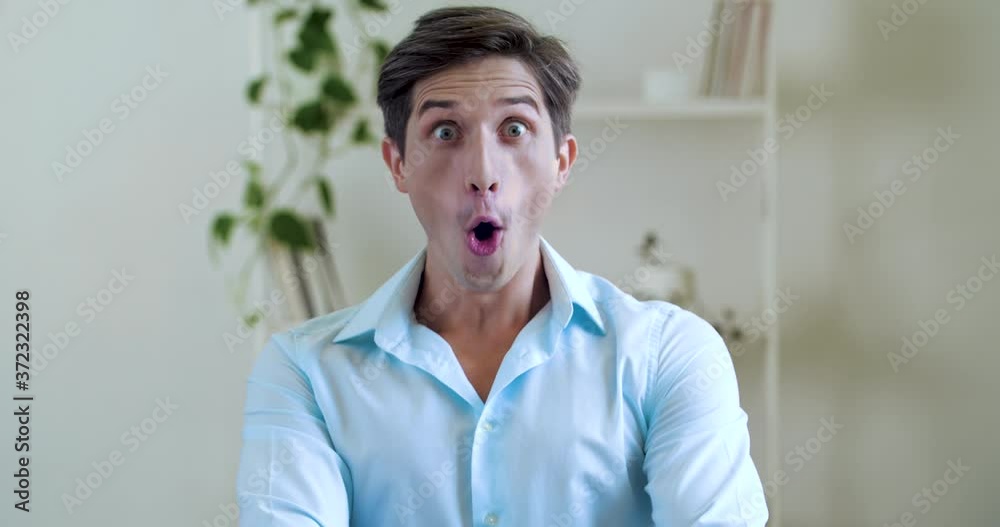 Portrait of funny young attractive man wears shirt, surprised, joyfully dances from good news. Close up male pleasantly shocked face, emotion of joy, wide open mouth, flirting looking at camera