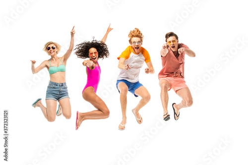 Fototapeta Naklejka Na Ścianę i Meble -  Excited multiethnic friends in sunglasses and flip flops jumping isolated on white
