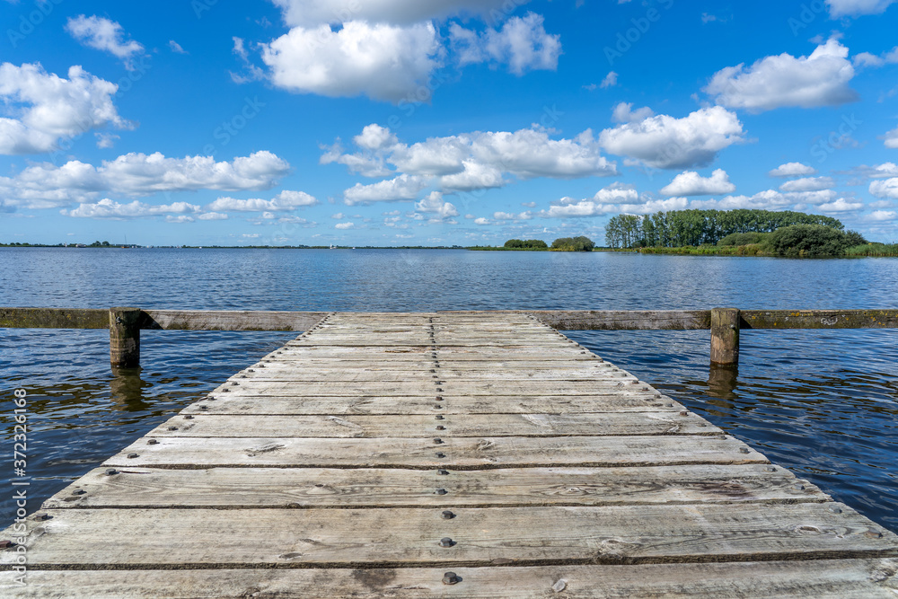 A wooden jetty made of planks sits above the water of a lake