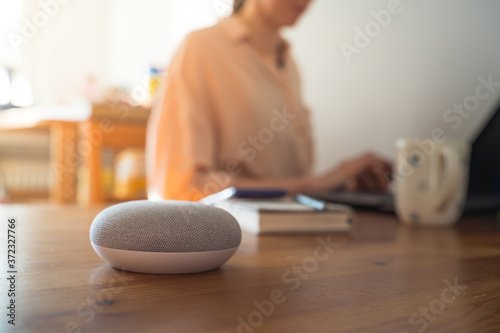 Smart ai voice speaker with woman in background.
