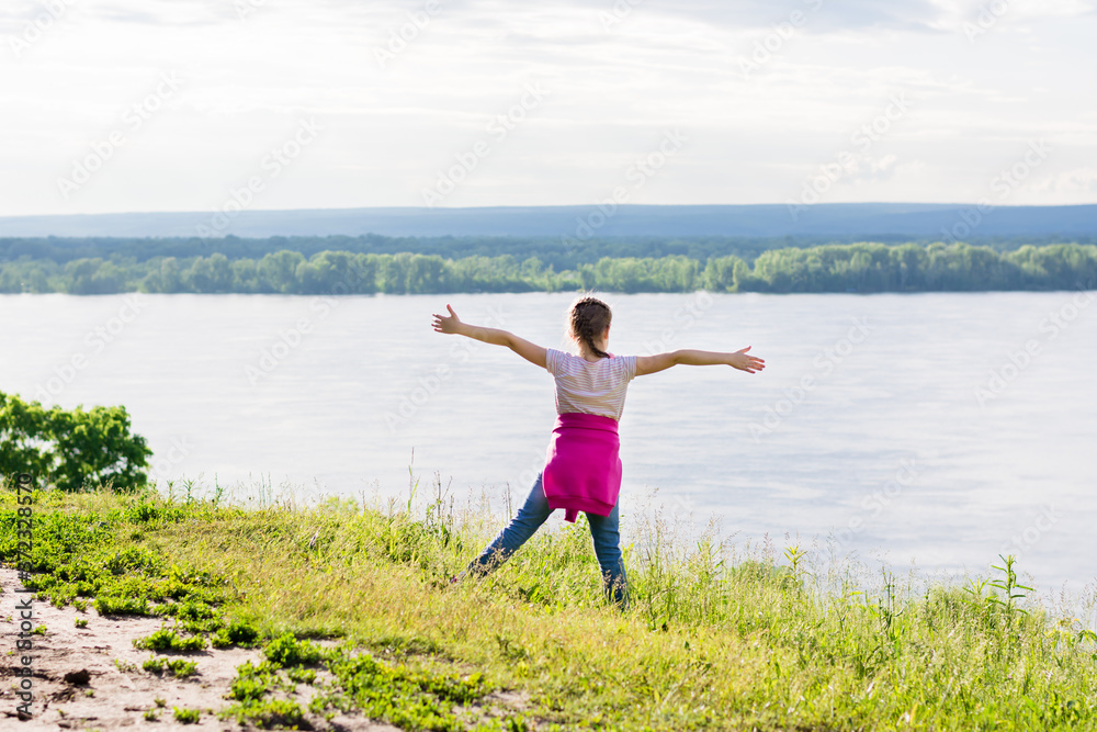 Local travel. Girl on an elevated bank of the river with arms outstretched. Summer tourism savage away from people Local travel. Girl on an elevated bank of the river with arms outstretched. Summer tourism savage away from people