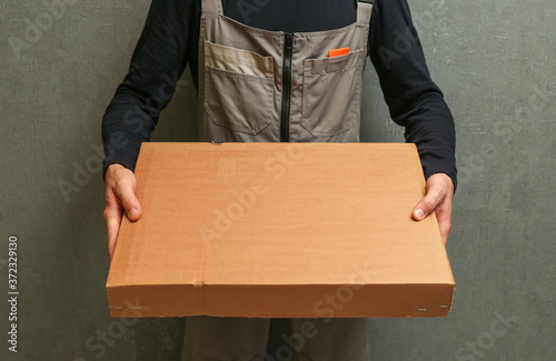 loader holding a cardboard box. a delivery service employee holds a box © Петр Смагин