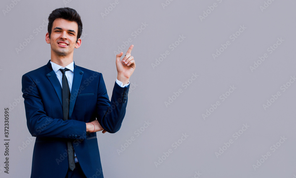 Young handsome businessman with beaming smile pointing with finger Young handsome businessman with beaming smile pointing with finger