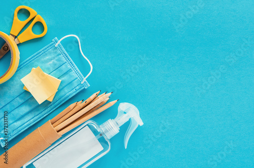 School supplies and coronavirus prevention items top view on a blue paper background. Back to school during corona virus pandemic concept