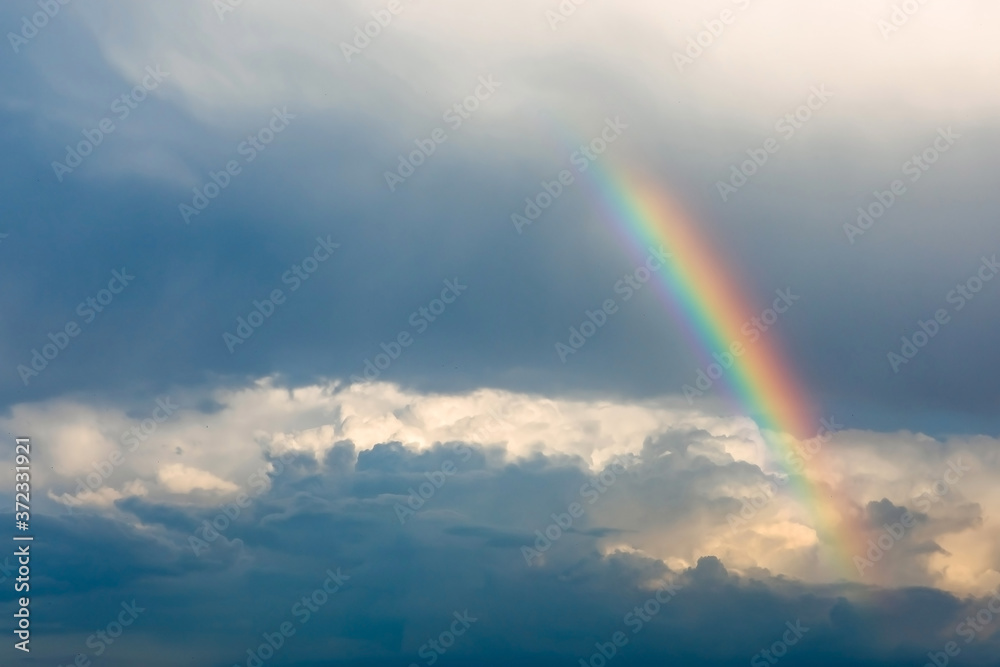 Rainbow over the clouds on blue sky background.