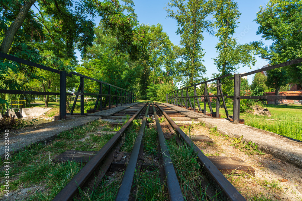 A drive across the Gasawka river for the narrow-gauge railway in the city of Żnin on a beautiful sunny day with a blue cloudless sky. A drive across the Gasawka river for the narrow-gauge railway in the city of Żnin on a beautiful sunny day with a blue cloudless sky.