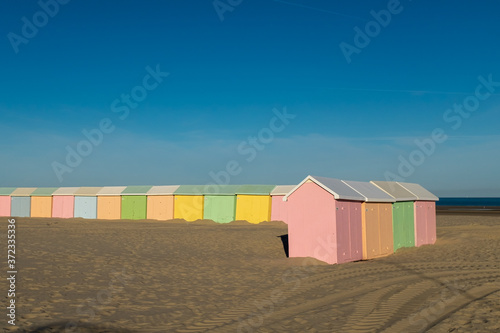 Multicolored beach huts lined up on the deserted beach of Berck in France
