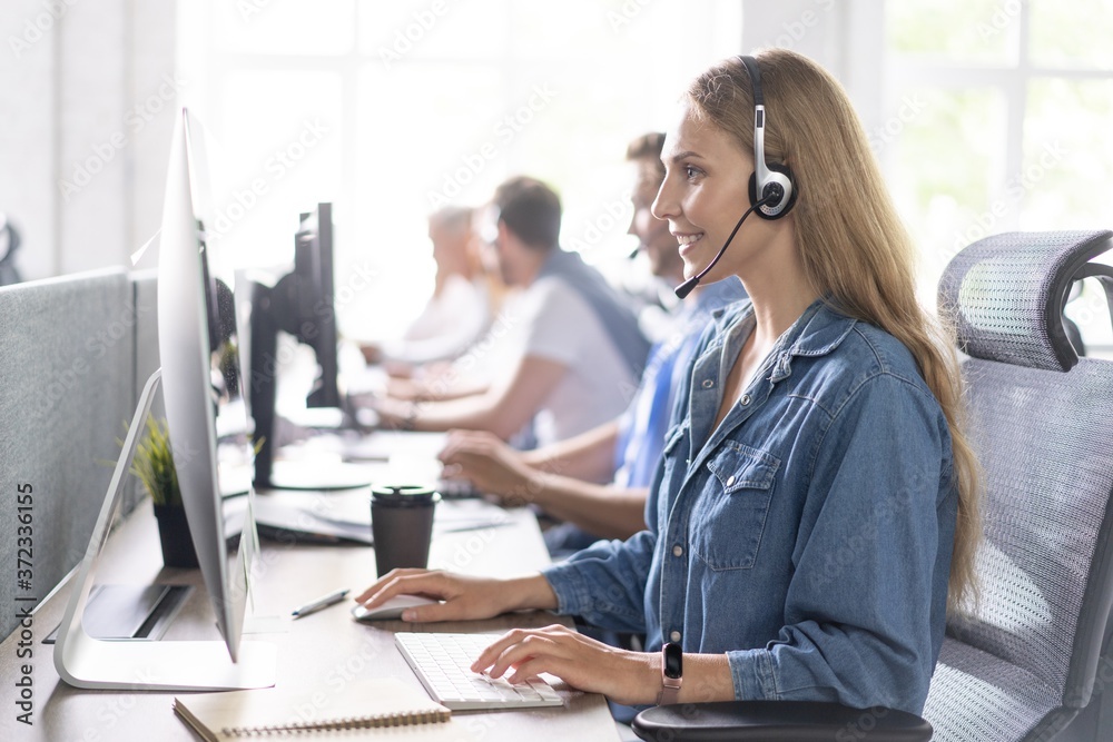 How can I help you? Beautiful call center workers in headphones are working at modern office.