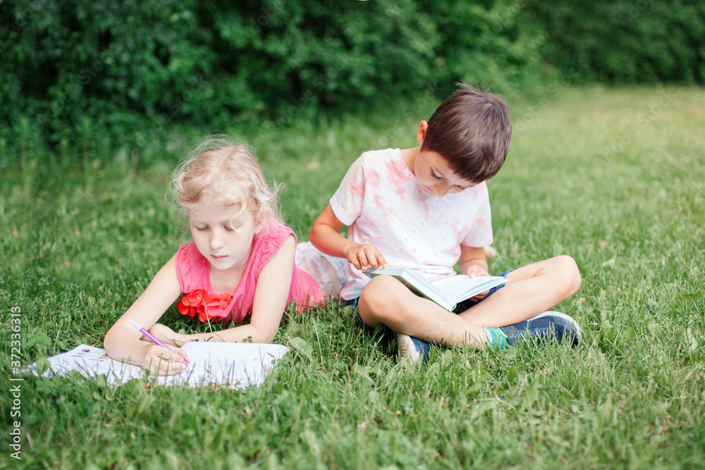 Elementary school students girl and boy doing homework outdoors. Children kids reading book and writing with pencil. Children education learning studying together. Friends classmates. Elementary school students girl and boy doing homework outdoors. Children kids reading book and writing with pencil. Children education learning studying together. Friends classmates.