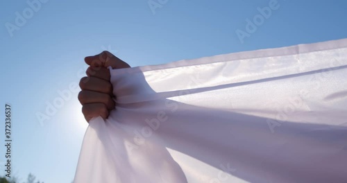 A man holds the flag of Belarus and stretches it with his arms in length against the background of the blue sky and the sun. photo