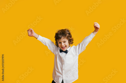 Happy boy laughs funny, screams in surprise, raising his hands up, the concept of childrens emotions.