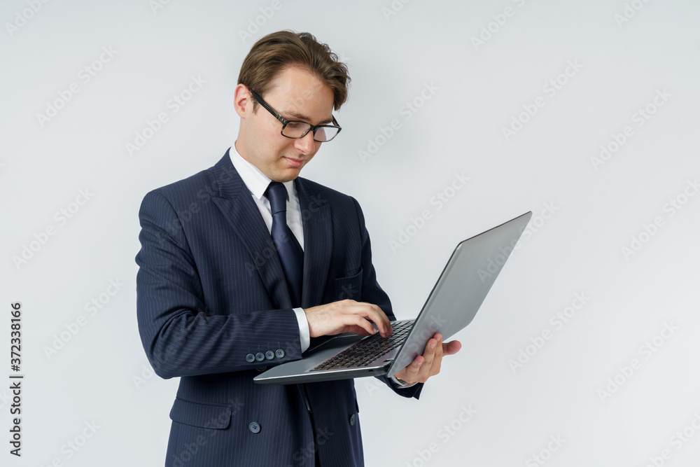 A businessman is holding a laptop in his hands, is typing with one hand. White background A businessman is holding a laptop in his hands, is typing with one hand. White background