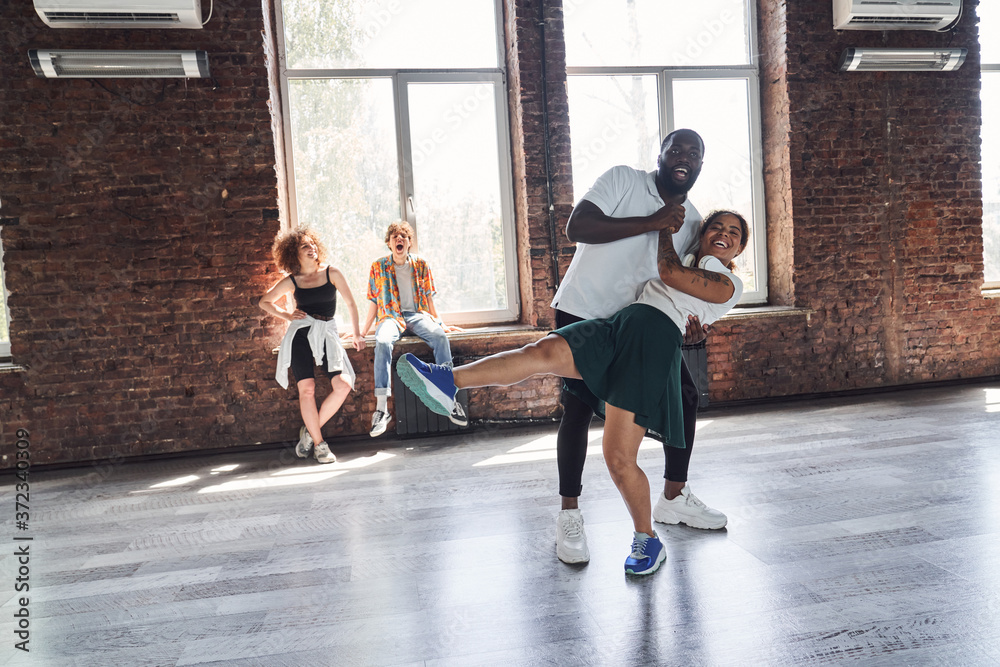 Fototapeta premium Happy Afro American woman and guy dancing hip-hop style in studio